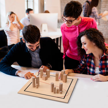 Eine Gruppe aus zwei Frauen und einem Mann sitz vor einem Systembrett. Sie planen strategische Entscheidungen zwischen 4 Teams. Zwei Teams und die anderen zwei Teams werden durch einen roten Faden abgegrenzt